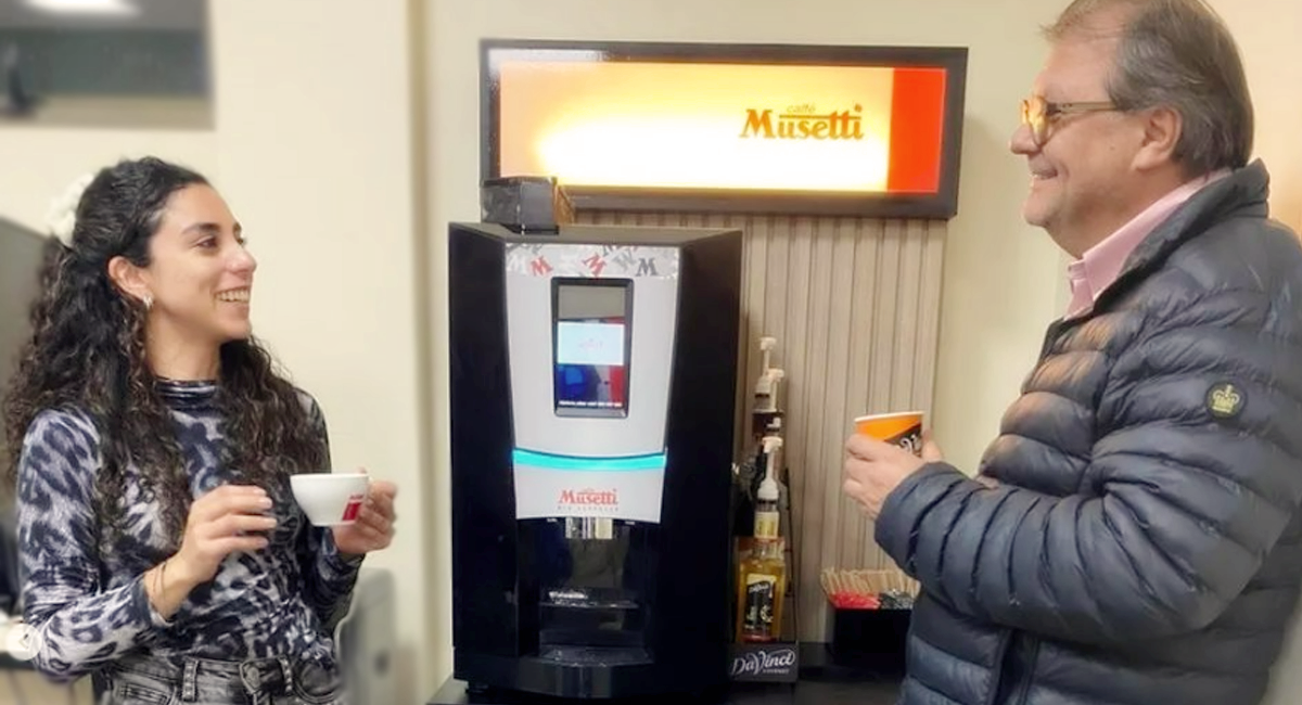 Mujer en oficina sirviéndose un café Musetti
